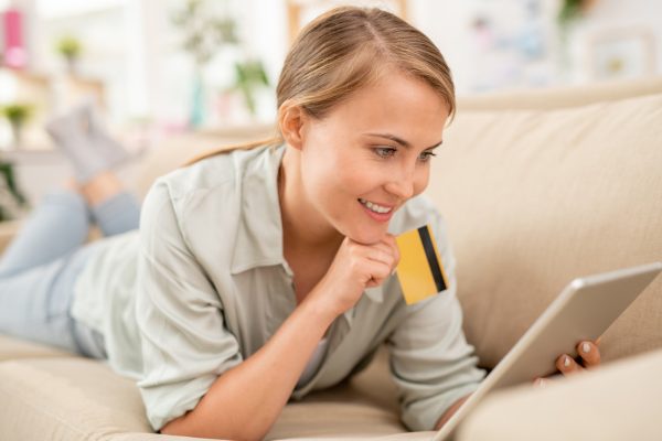 Consumer with plastic card and touchpad scrolling through online goods